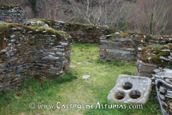 Castro de Coaña. Grupo de cabañas en el barrio norte con un mortero de cazoletas en primer plano.